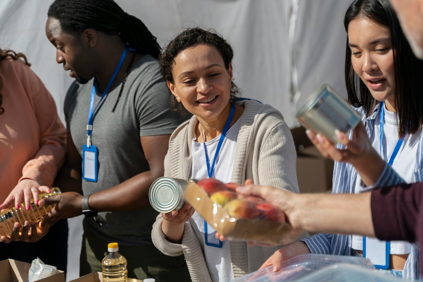 Volontari smistano e distribuiscono generi alimentari durante un evento di beneficenza all'aperto.