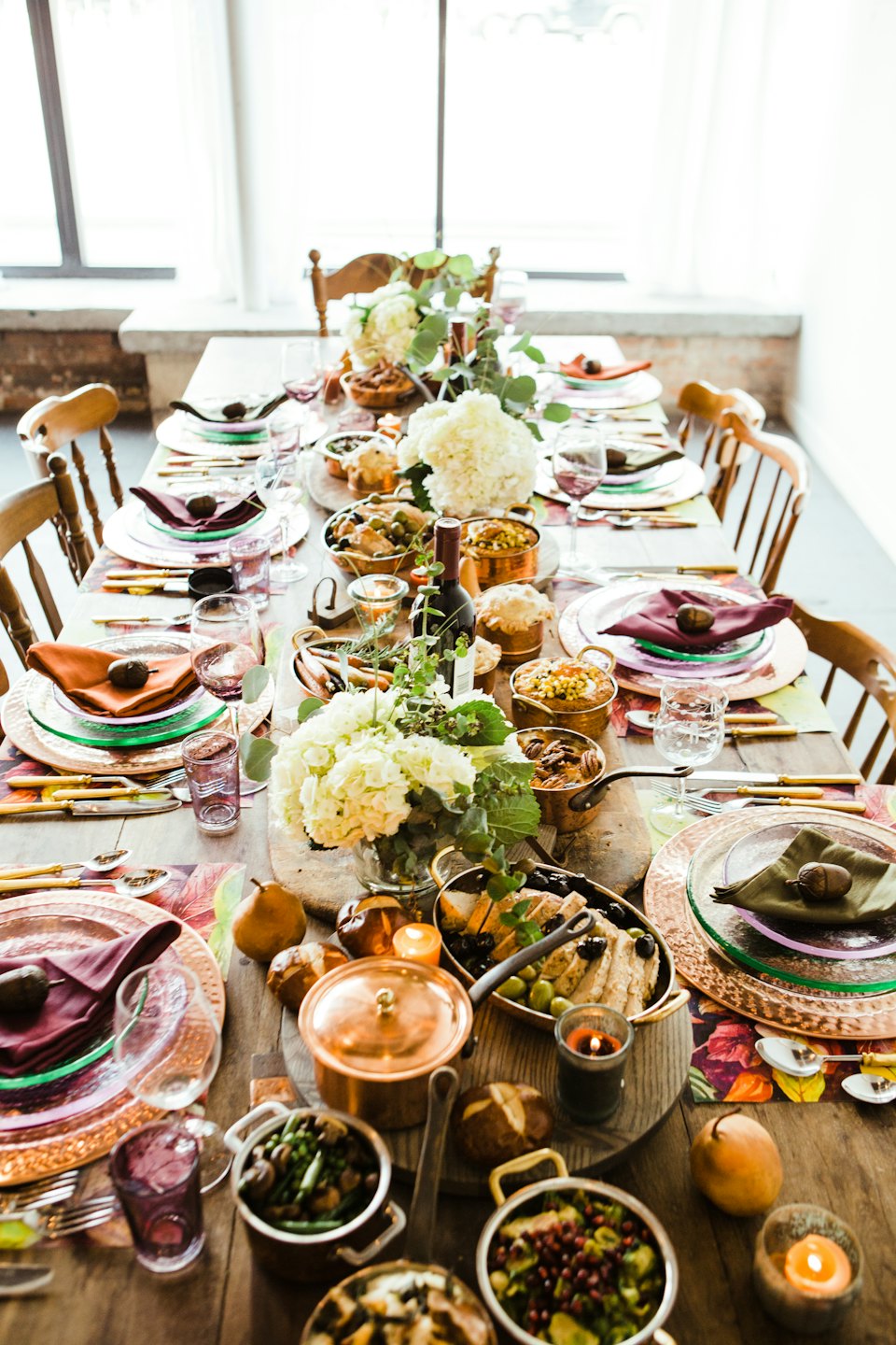 Tavola da pranzo festiva apparecchiata con cibo e decorazioni autunnali.